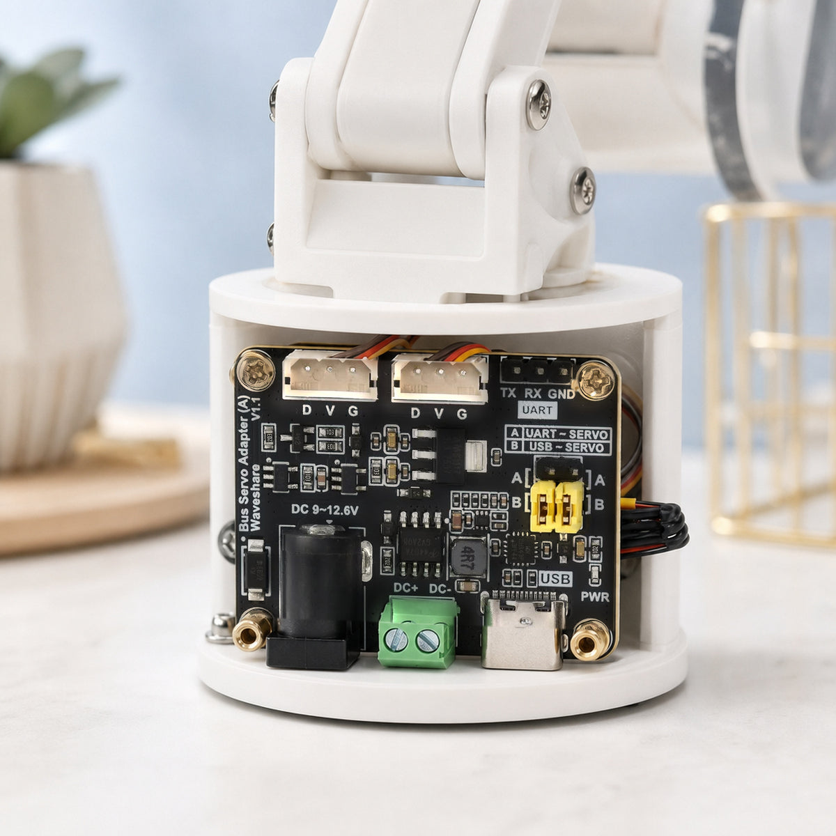 Waveshare bus servo adapter board – the board mounted inside the base of a small white 3D-printed robot arm with cables routed to it