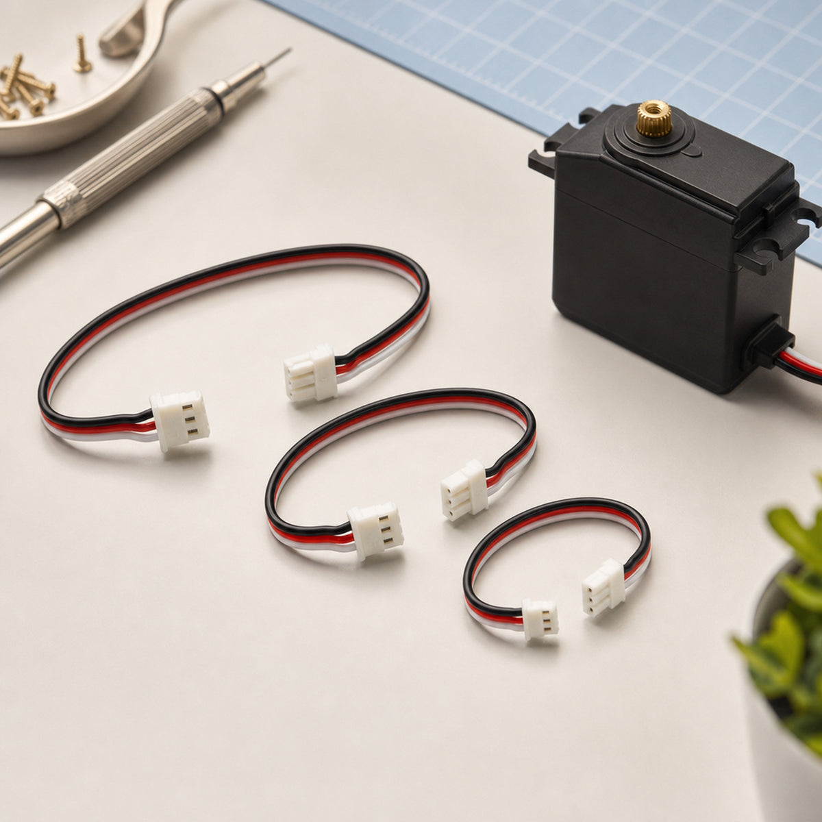 Feetech 3-pin servo cables – a neat bundle of 3-pin servo cables of three lengths next to a black bus servo on a workbench
