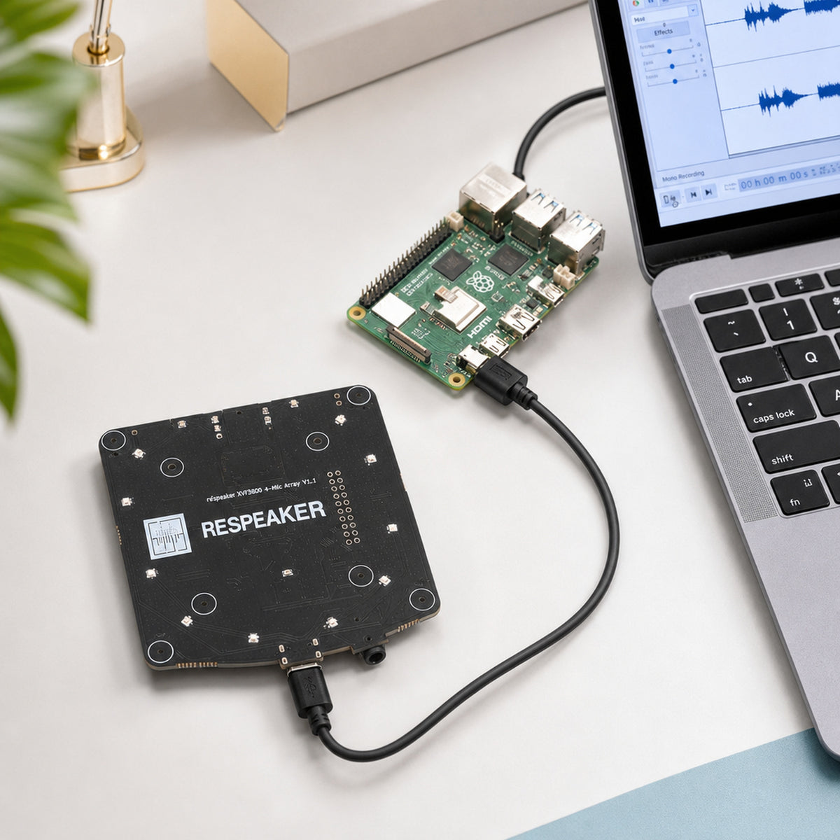ReSpeaker XVF3800 4-mic array – top-down on a workbench: the mic array board plugged by USB into a Raspberry Pi 5 with a laptop showing an audio waveform