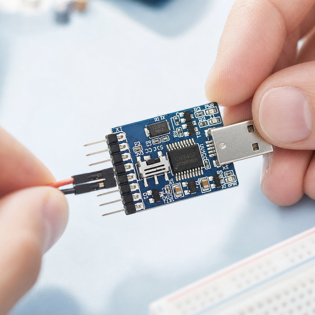 CH340 USB to UART adapter – close-up of an engineer's fingers connecting a jumper wire to the adapter's header pins