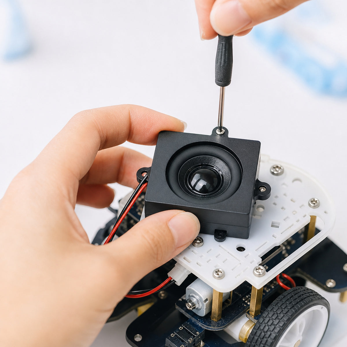 Mono enclosed speaker 4 ohm 5 W – close-up of a maker's hands screwing the speaker onto a small robot chassis