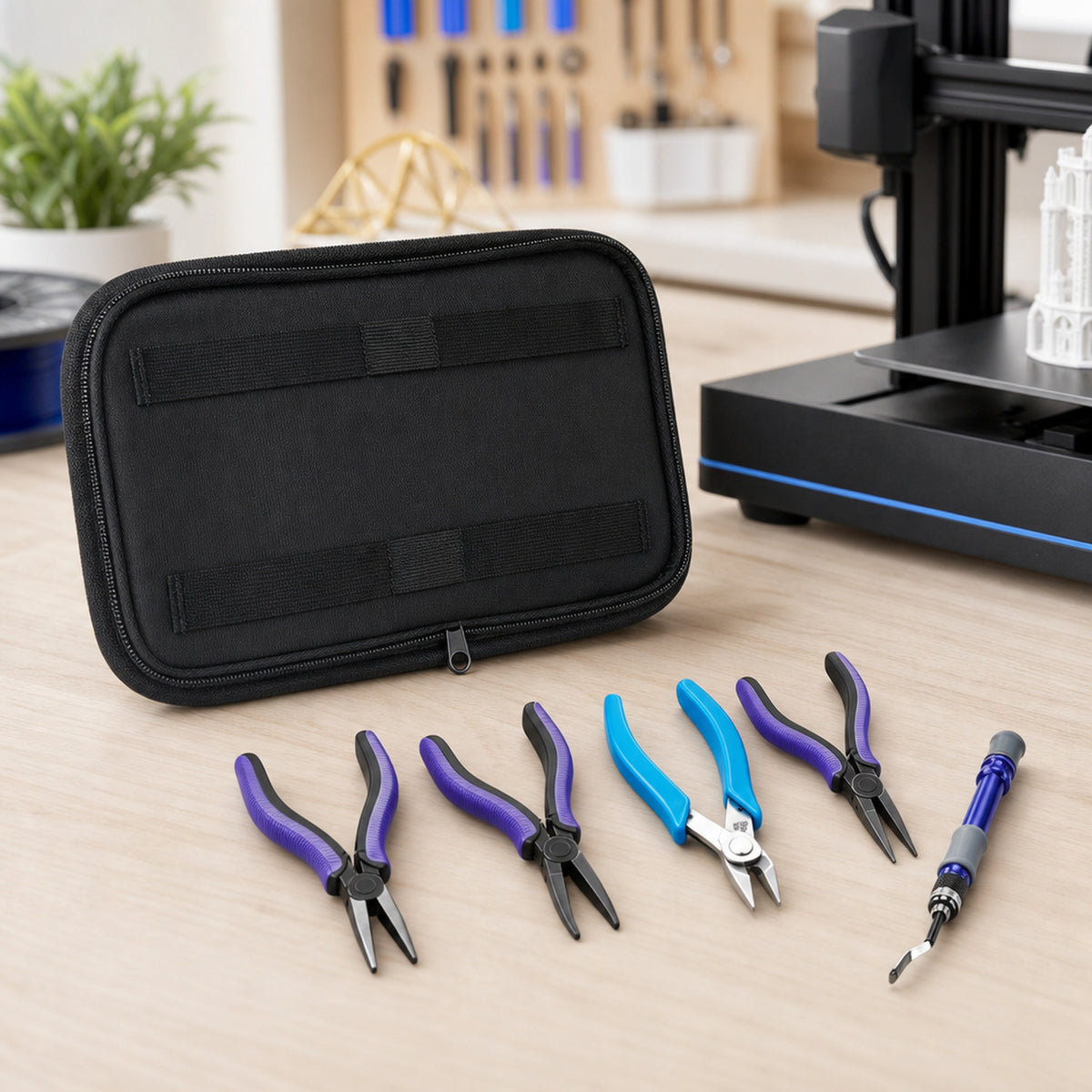 3D print finishing tool kit – the closed zip case and the five tools laid out on a light wooden desk beside a desktop 3D printer